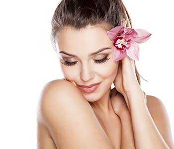 Healthy skin of young beautiful woman face with a flower in her hairs 
