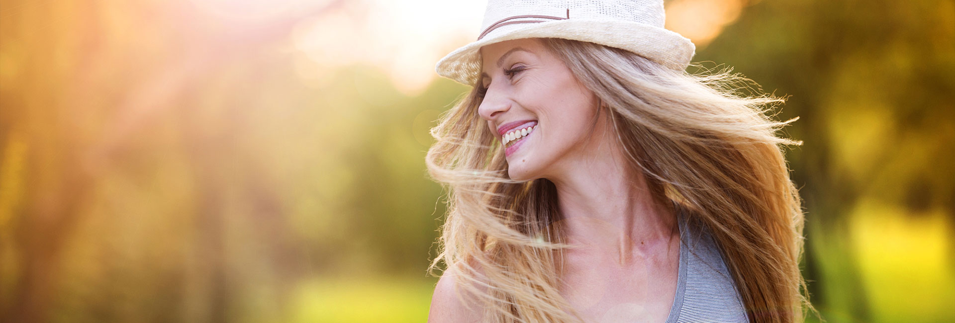 Woman in white hat laughing in sunny park